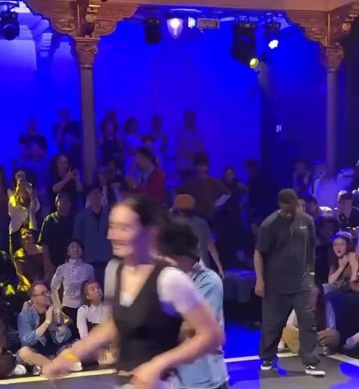 A dancer stepping out at a dance battle under blue stage lights